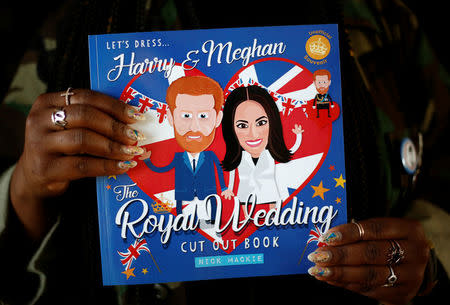 Ishea Brown, who plans to hold a Royal wedding viewing party with 19 of her friends, complete with fascinators and Hennessy, holds a Harry and Meghan cut out book at her apartment in Seattle, Washington, U.S., May 14, 2018. Picture taken May 14, 2018. REUTERS/Lindsey Wasson