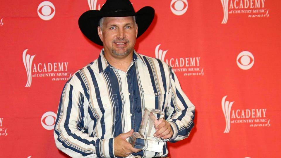 Garth Brooks holding Academy of country music award on red carpet