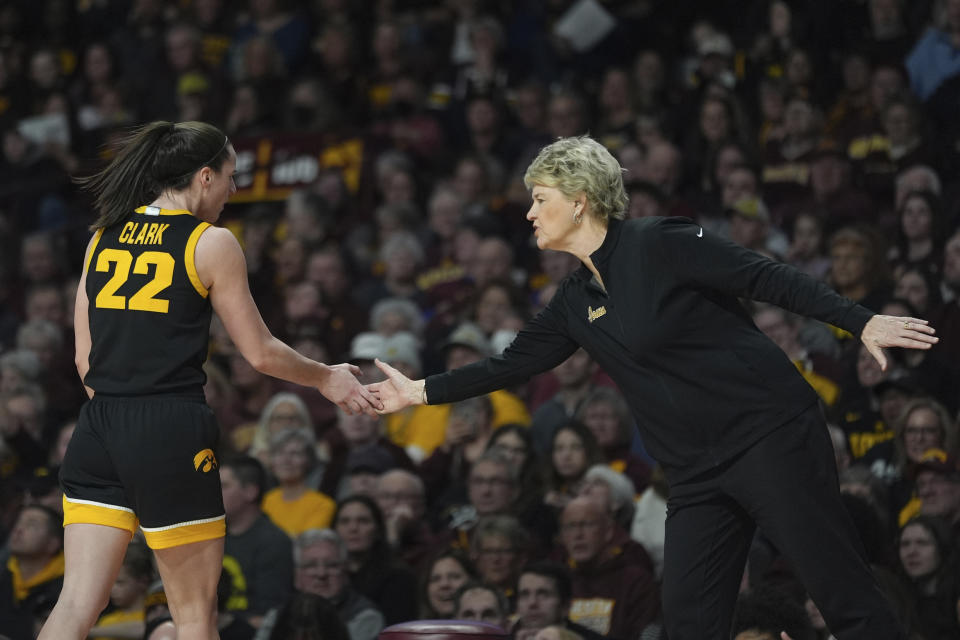 Iowa guard Caitlin Clark (22) and head coach Lisa Bluder high-five during the first half of an NCAA college basketball game against Minnesota, Wednesday, Feb. 28, 2024, in Minneapolis. (AP Photo/Abbie Parr)