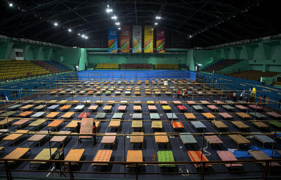 Indian workers arrange beds to prepare a quarantine center at the Sarusojai sports complex in Gauhati, India, Saturday, March 28, 2020. The new coronavirus causes mild or moderate symptoms for most people, but for some, especially older adults and people with existing health problems, it can cause more severe illness or death. (AP Photo/Anupam Nath)