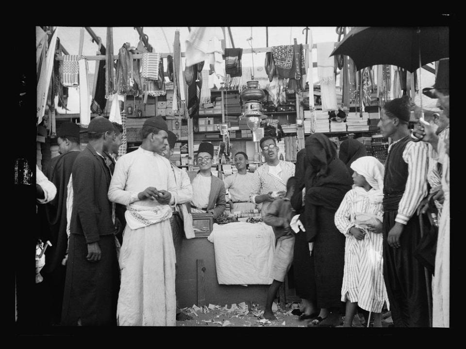 A black and white photo of people surrounding a market.