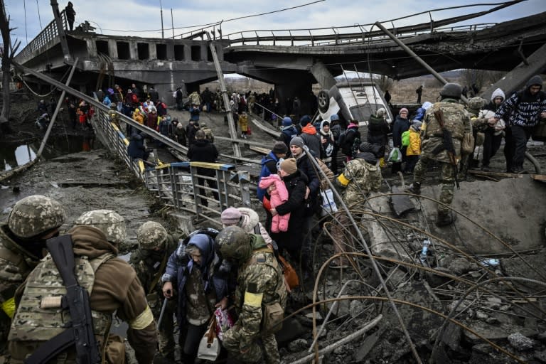 People cross a destroyed bridge as they evacuate the city of Irpin, northwest of Kyiv, during heavy shelling (AFP/Aris Messinis)