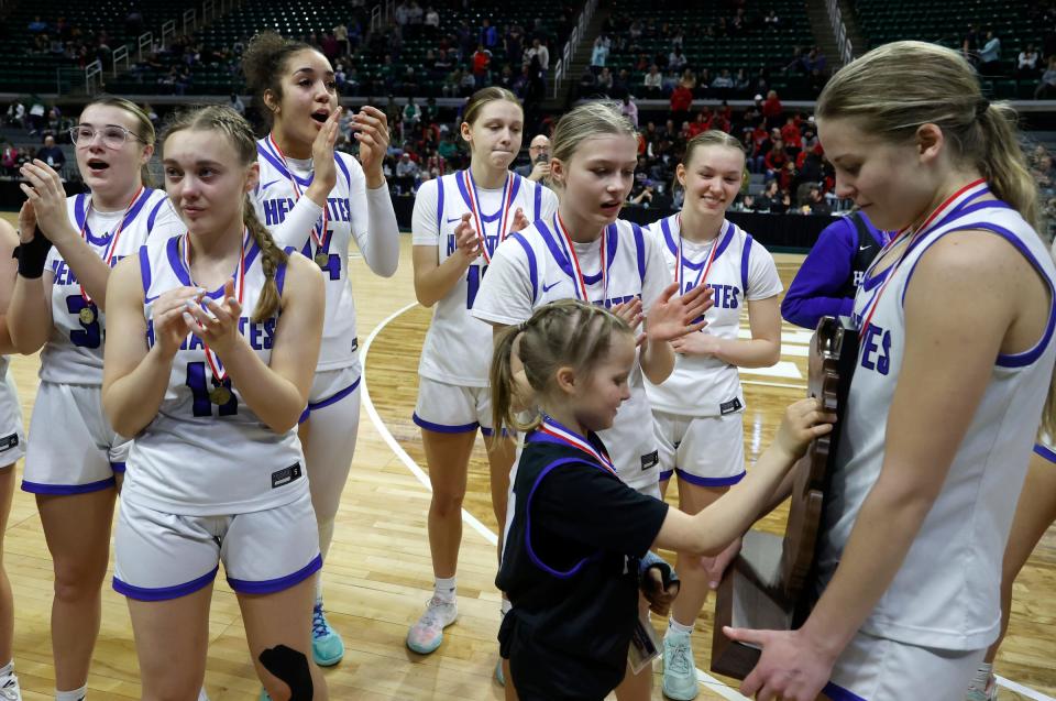 Nora Reichel, the daughter of Ishpeming coach Ryan Reichel, checks out the championship trophy as the team celebrates with fans in the stands after the 73-54 win over Kingston in the Division 4 girls basketball state final at Breslin Center on Saturday, March 23, 2024.