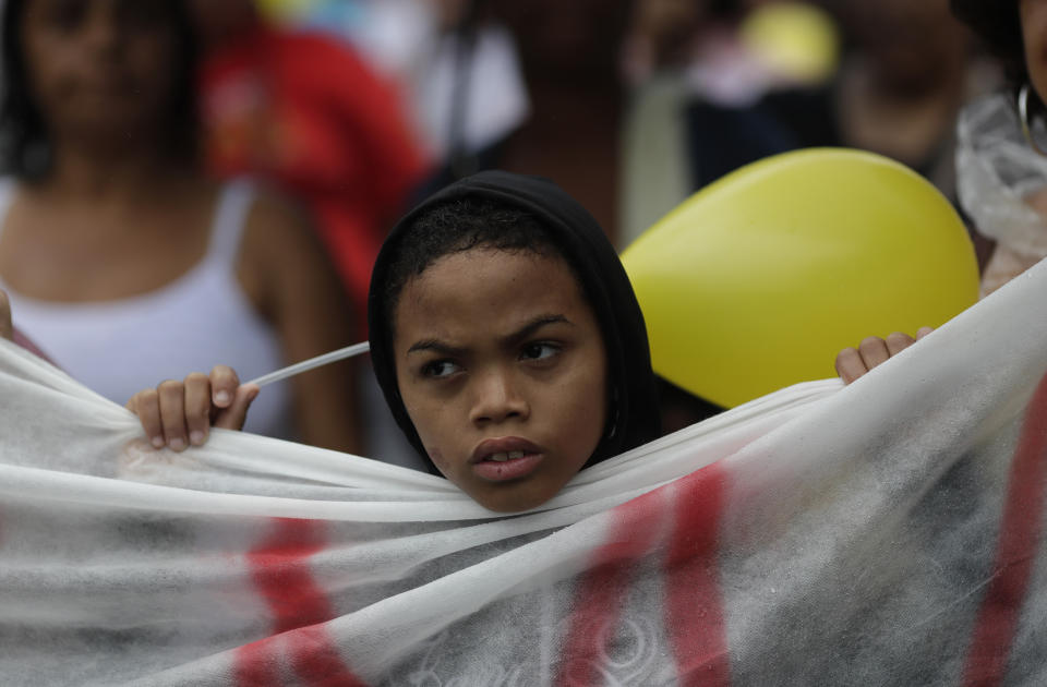 A protester attends a gathering in memory of the late 8-year-old Ágatha Sales Félix, whose photo of her clutching a yellow balloon is circulating online, as people demand an end to the violence in the Alemao complex slum of Rio de Janeiro, Brazil, Sunday, Sept. 22, 2019. Félix was hit by a stray bullet Friday amid what police said was shootout with suspected criminals. However, residents say there was no shootout, and blame police. (AP Photo/Silvia Izquierdo)