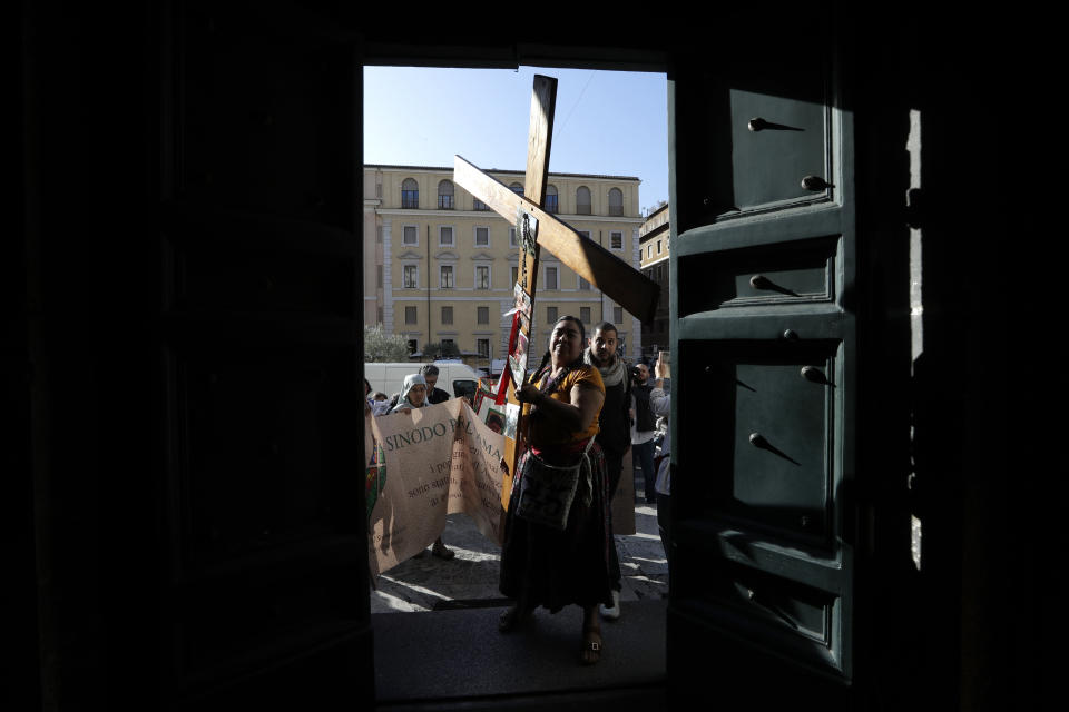 A woman carrying a cross enters in the Santa Maria in Transpontina Church, during a Via Crucis (Way of the Cross) procession of members of indigenous populations from St. Angelo Castle to the Vatican, Saturday Oct. 19, 2019. Pope Francis is holding a three-week meeting on preserving the rainforest and ministering to its native people as he fended off attacks from conservatives who are opposed to his ecological agenda. (AP Photo/Andrew Medichini)