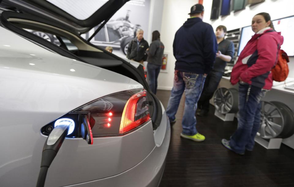 Customers check out a new Tesla all electric car, Monday, March 17, 2014, at a Tesla showroom inside the Kenwood Towne Centre in Cincinnati. Ohio auto dealers are sparring at the Statehouse with the California-based Tesla, which is selling it's next generation electric cars from three Ohio storefronts. Lawmakers in Ohio and other states are trying to block Tesla direct sales on grounds they undercut traditional auto dealerships. (AP Photo/Al Behrman)