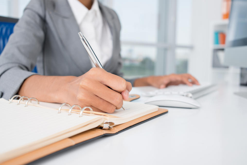 Close-up of female hands making notes in the notepad at office