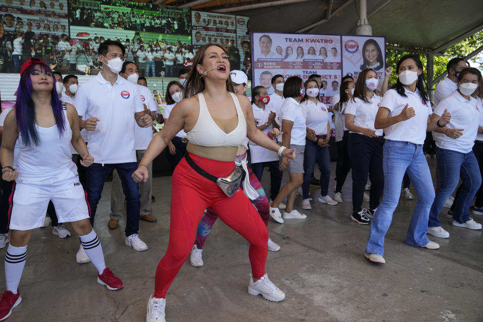 A dancer entertains the crowd beside Quezon City Mayor Joy Belmonte, second from right, as she starts her re-election campaign in Quezon City, Philippines on Friday, March 25, 2022. Candidates for thousands of provincial, town and congressional posts started campaigning across the Philippines Friday under tight police watch due to a history of violent rivalries and to enforce a lingering pandemic ban on handshakes, hugging and tightly packed crowds that are a hallmark of often circus-like campaigns. (AP Photo/Aaron Favila)