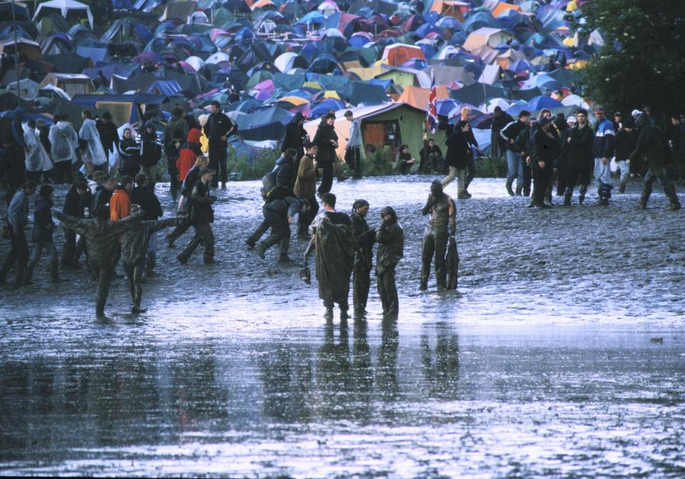 A general view of festival-goers covered in mud at a rain-soaked Glastonbury Festival, United Kingdom, 1997. (Photo by Martyn Goodacre/Getty Images)