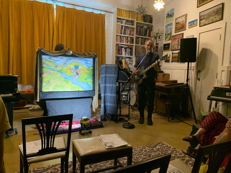 In a studio next to their Travis Heights home, musician and record producer Brian Beattie performs his "El Camino Real de los Tejas Crankie Suite," while artist Valerie Fowler (hidden behind the little stage) operates the "crankie" roll-out scenery that took her more than a year to paint.