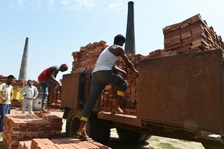 This photograph taken on September 16, 2017, shows Indian labourers loading bricks onto a tractor trolley at a brick kiln on the outskirts of Amritsar