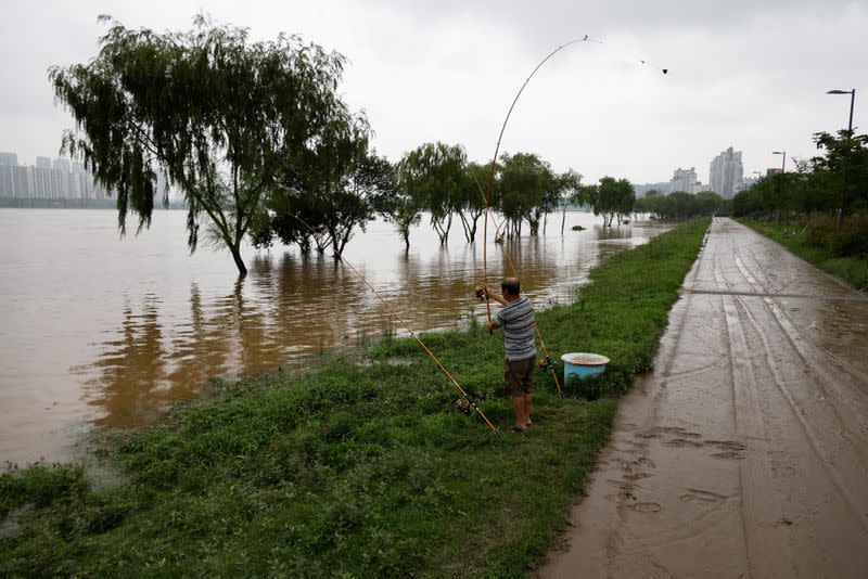 A man fishes along a flooded Han River park in Seoul