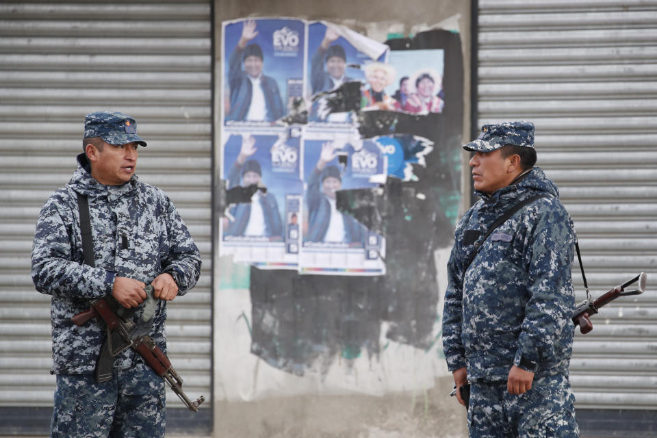 Soldiers stand in front of electoral posters of former President Evo Morales in El Alto, outskirts of La Paz, Bolivia, Tuesday, Nov. 12, 2019. Bolivia faced political vacuum Tuesday, while Morales fled the country on a Mexican plane following weeks of widespread protests fed by allegations of electoral fraud in the Oct. 20 presidential election that he claimed to have won (AP Photo/Natacha Pisarenko)