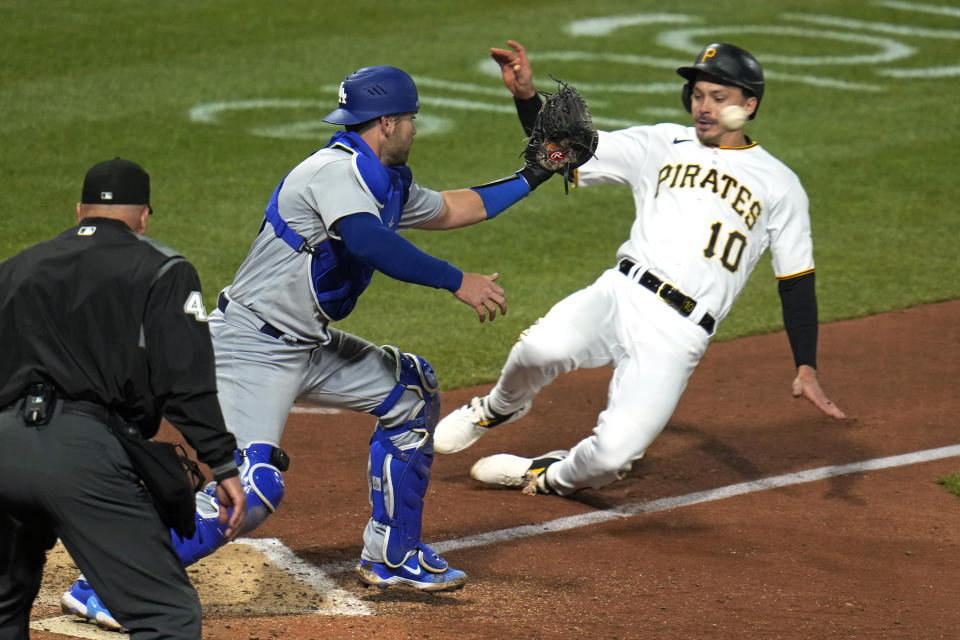 Los Angeles Dodgers catcher Austin Wynns, center, gets the force out at home plate on Pittsburgh Pirates Bryan Reynolds (10) during the seventh inning of a baseball game in Pittsburgh, Wednesday, April 26, 2023. (AP Photo/Gene J. Puskar)