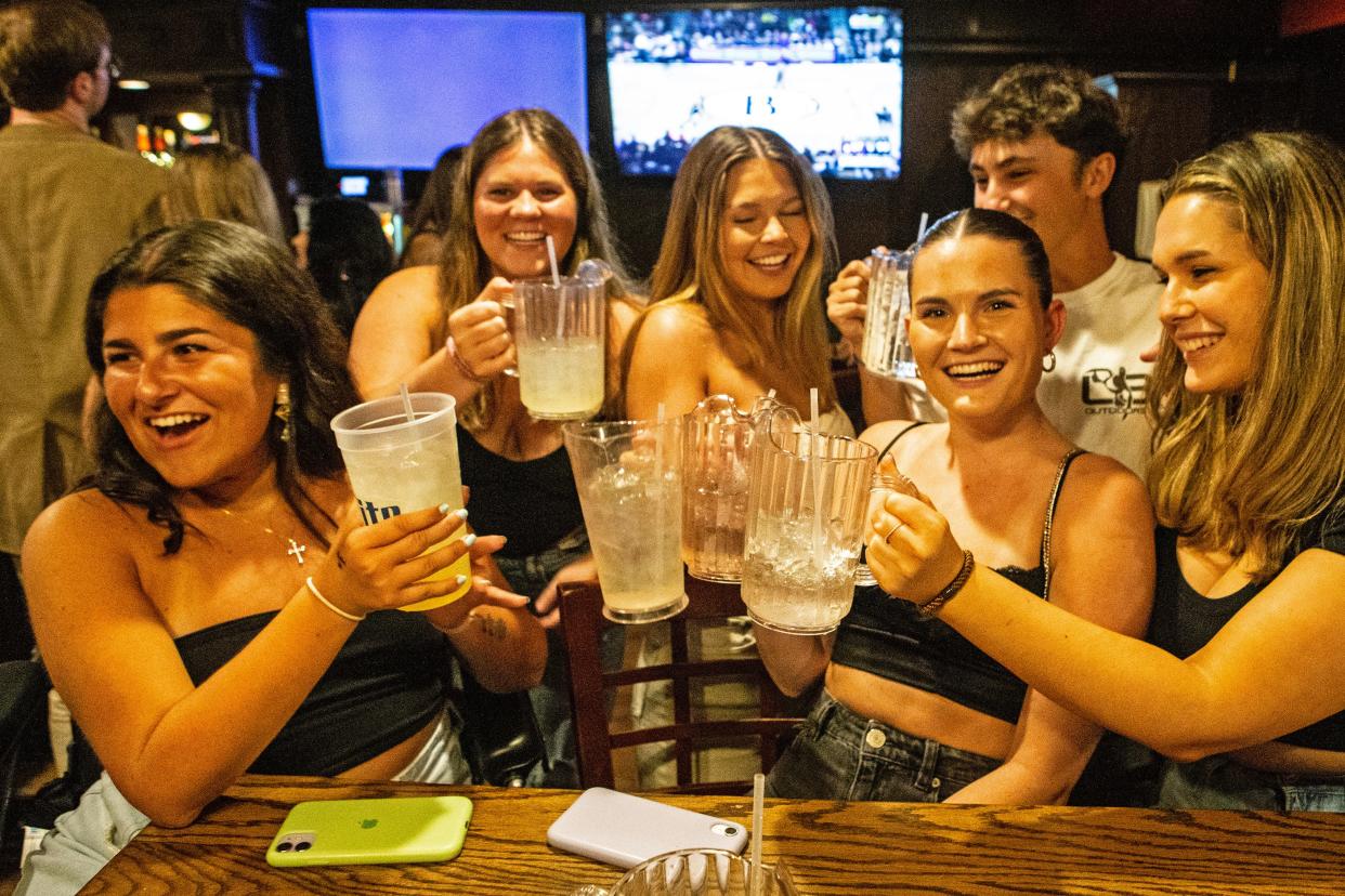 University of Delaware students enjoy drinks, including the popular personal pitchers or "mega pints" of mixed drinks at the Deer Park Tavern in Newark, Thursday, April 20, 2023. 