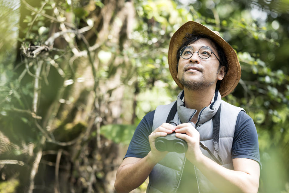 Senior Asian Man watching bird watching with binoculars. (Getty Images)