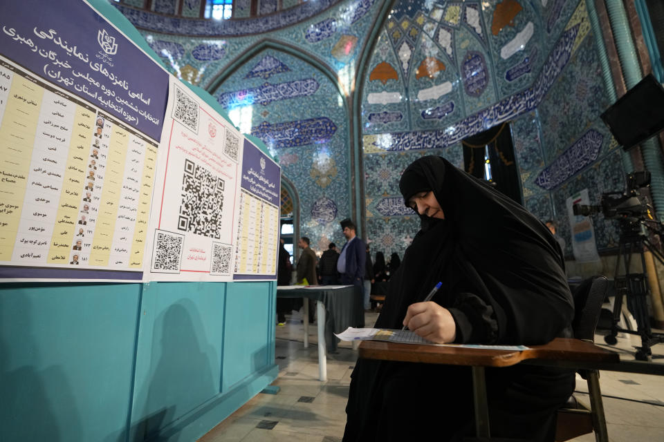 A voter fills out her ballot in the parliamentary and assembly of experts elections at a polling station in Tehran, Iran, Friday, March 1, 2024. Iran began voting Friday in its first elections since the mass 2022 protests over its mandatory hijab laws after the death of Mahsa Amini, with questions looming over just how many people will turn out for the poll. (AP Photo/Vahid Salemi)