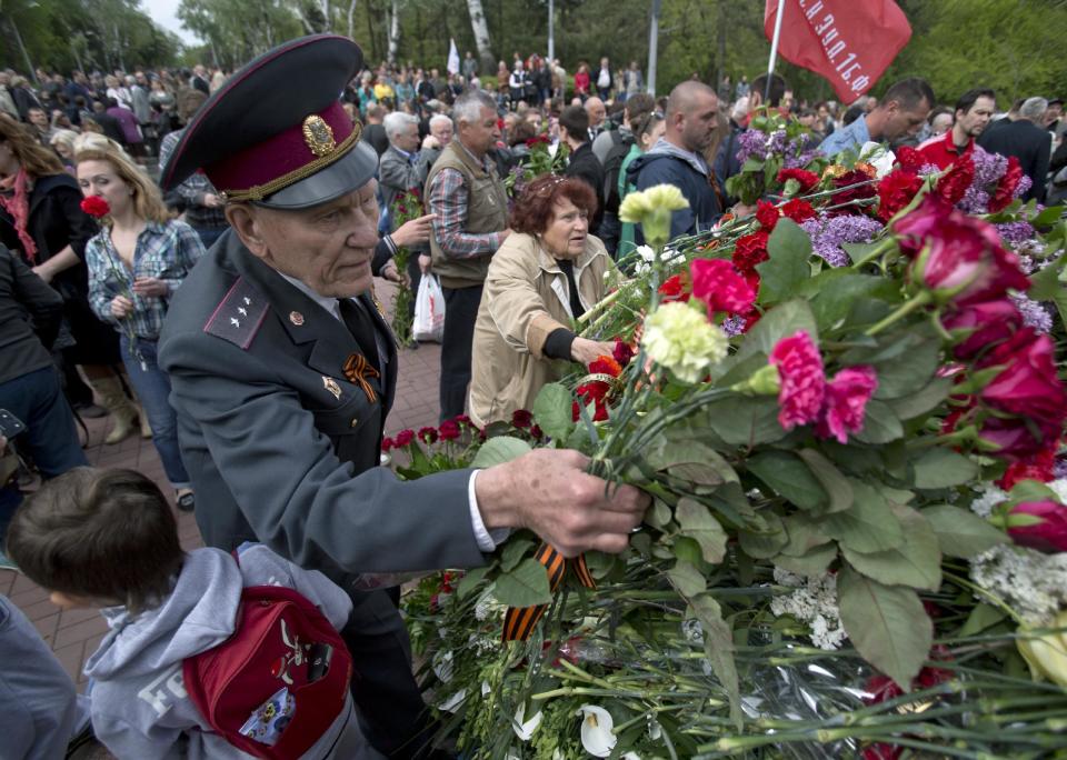 A WWII veteran lays flowers at a war memorial during Victory Day celebrations in Odessa, Ukraine, Friday, May 9, 2014. In the Black Sea port of Odessa, which last week was rocked by violent clashes between pro-Russian forces and supporters of the central government that left nearly 50 people died, the local governor issued an order banning public display of Russian flags. (AP Photo/Vadim Ghirda)