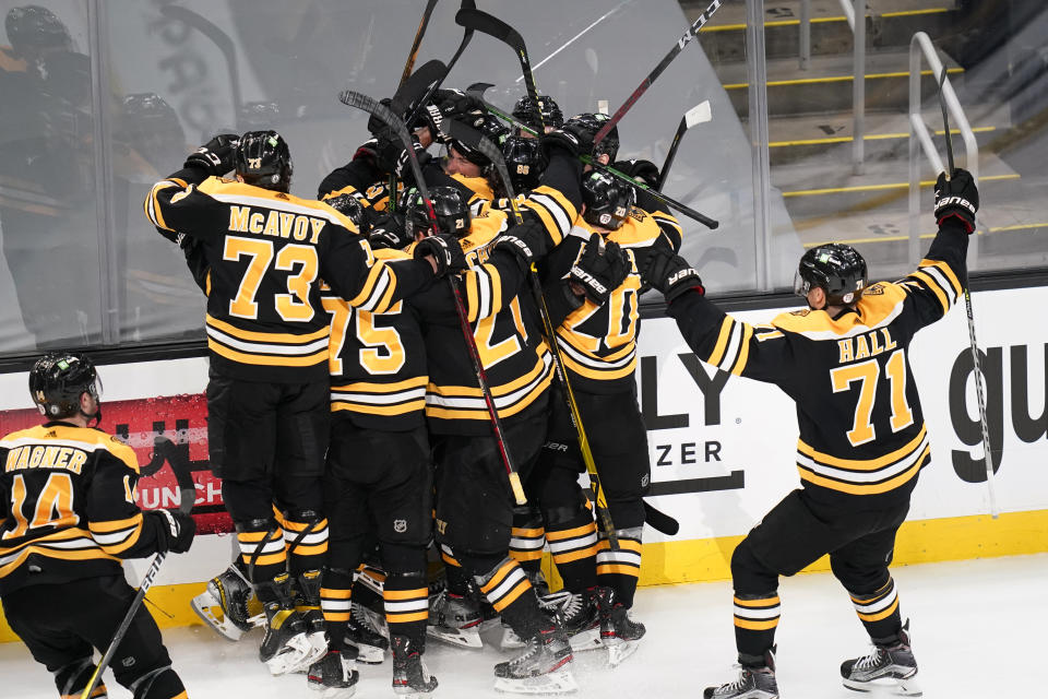 FILE - Teammates surround Boston Bruins right wing Craig Smith after his game-winning goal against the Washington Capitals during a second overtime period of Game 3 of an NHL hockey Stanley Cup first-round playoff series in Boston, in this Wednesday, May 19, 2021, file photo. The Bruins won 3-2. A pandemic postseason outside a bubble has led to some thrilling hockey after an exhausting, condensed 56-game grind. (AP Photo/Charles Krupa, FIle)