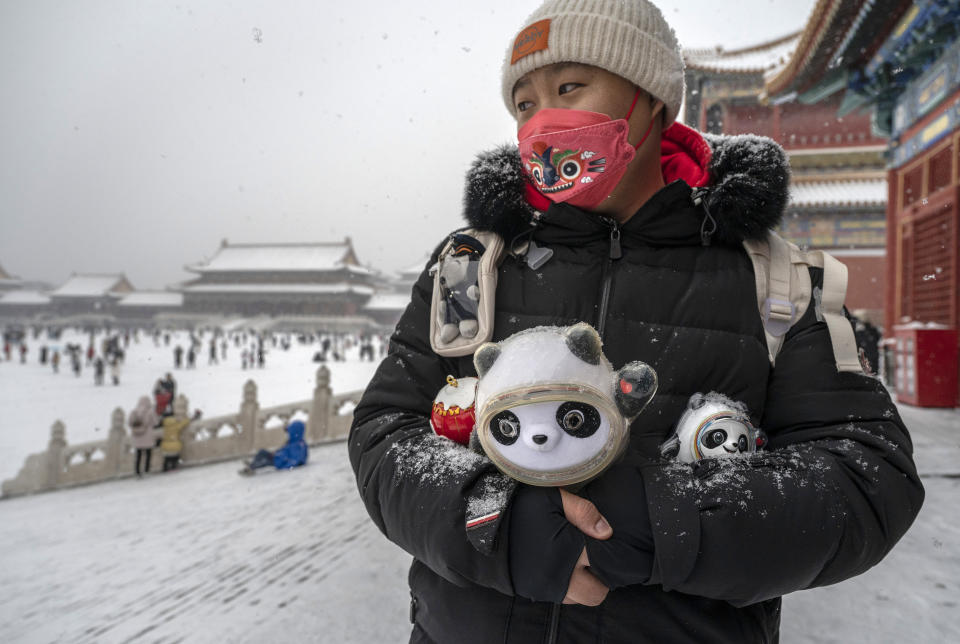 BEIJING, CHINA - FEBRUARY 13: A man holds Beijing 2022 Winter Olympics mascot Bing Dwen as he walks in the iconic Forbidden City during a snowfall on February 13, 2022 in Beijing, China. China's capital is hosting the Beijing 2022 Winter Olympics which closes on February 20th. (Photo by Kevin Frayer/Getty Images)