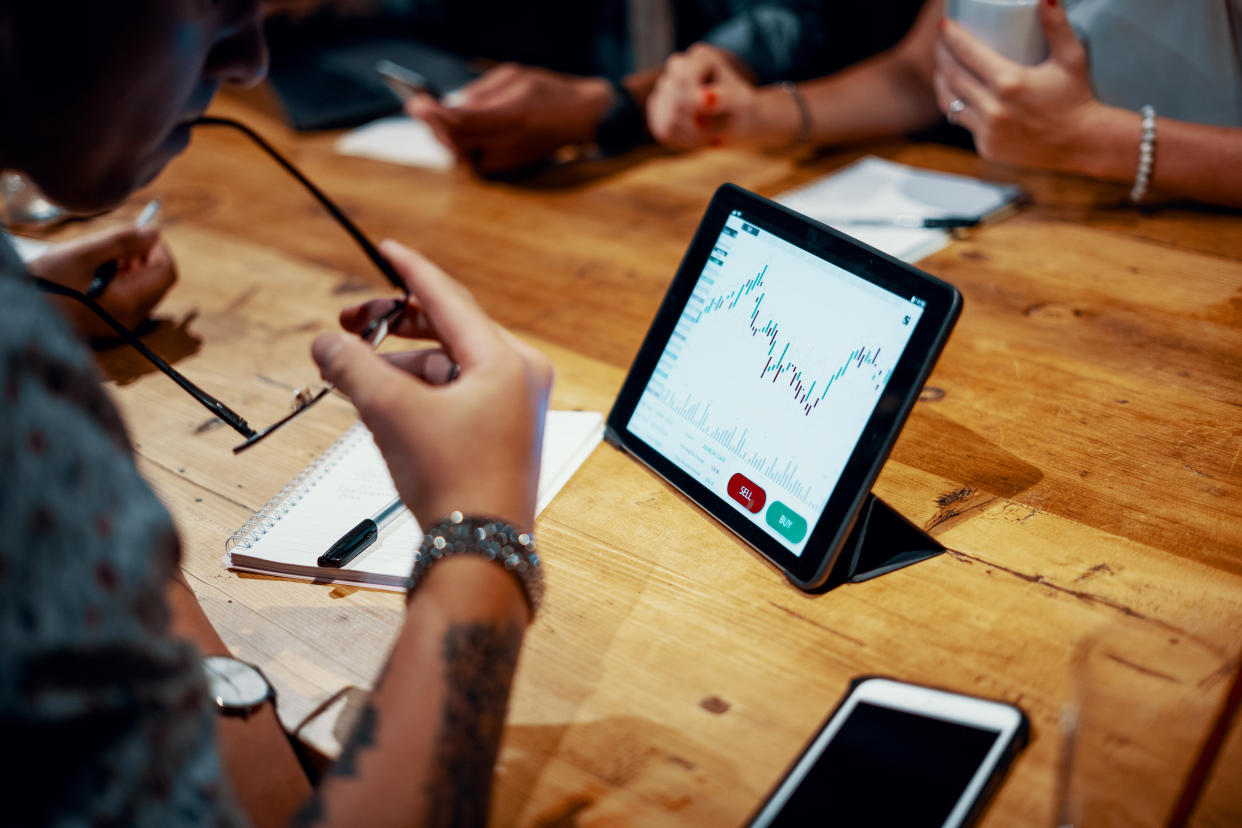 Mixed group of millennial aged friends discuss investing and cryptocurrency trading at a cafe