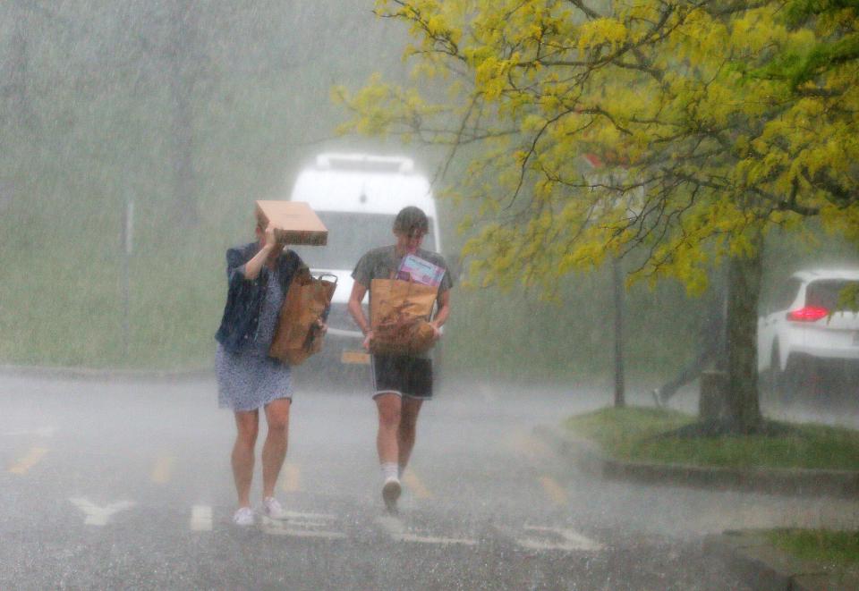 People walk to their cars during a heavy rain fall after shopping on Independent Way in Brewster May 16, 2022. 