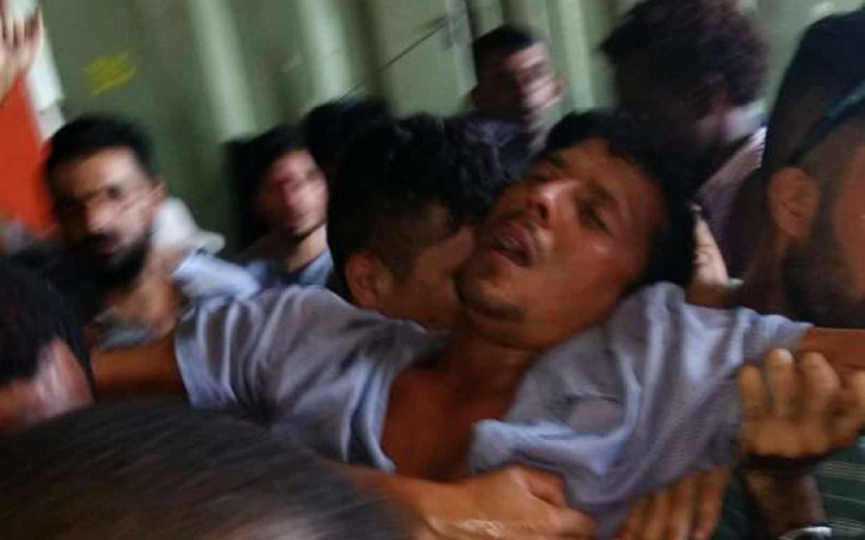 A man is helped after collapsing from stress as asylum-seekers refuse to leave the Manus Island regional refugee processing centre - AFP