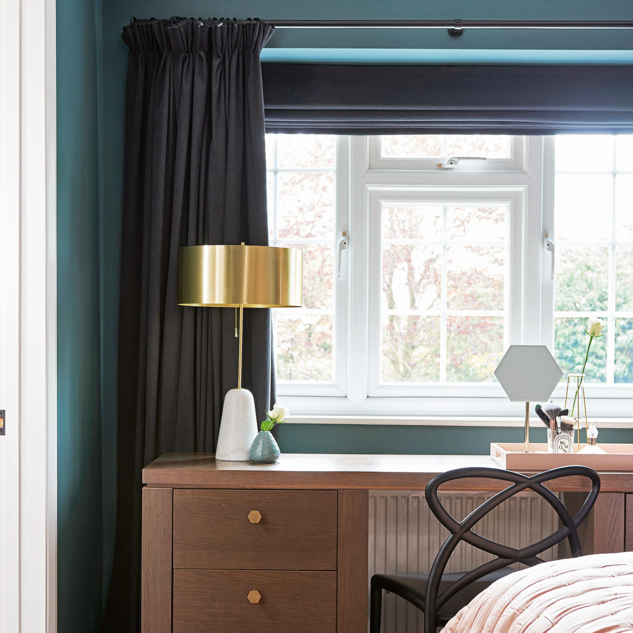  Bedroom in navy with blinds and curtains over wooden desk. 