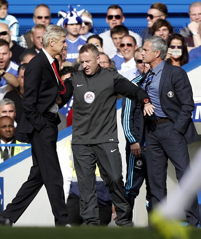 Chelsea's manager Jose Mourinho (R) and Arsenal's counterpart Arsene Wenger are kept apart by an official during their English Premier League match at Stamford Bridge in London, in October 2014