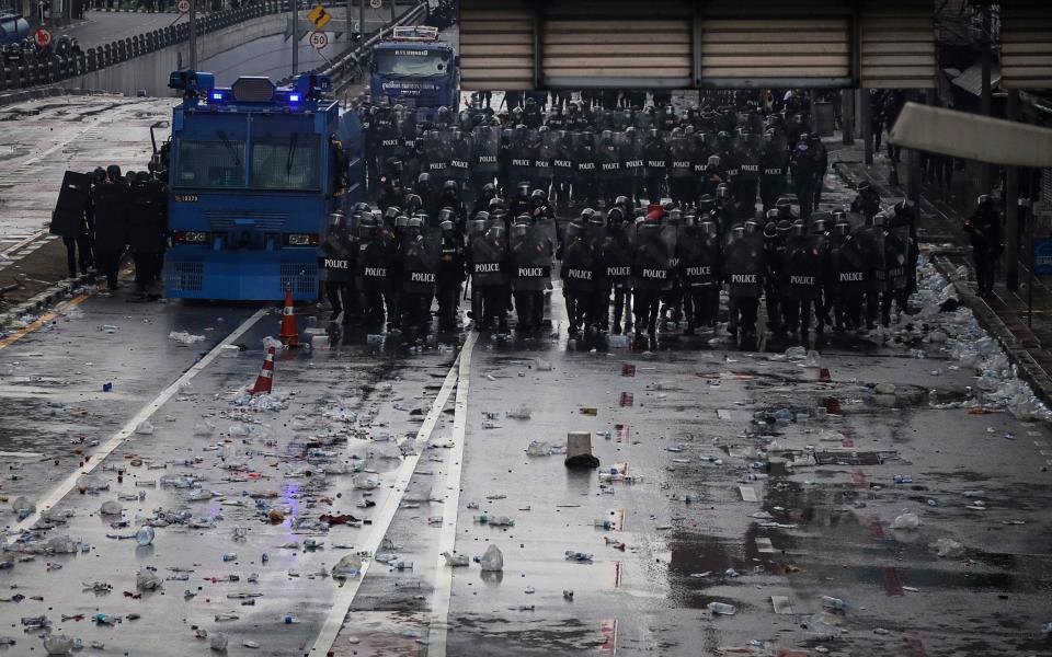 Riot police stand guard on a street strewn with debris after confronting anti-government protesters on Saturday -  Lauren DeCicca/Getty Images