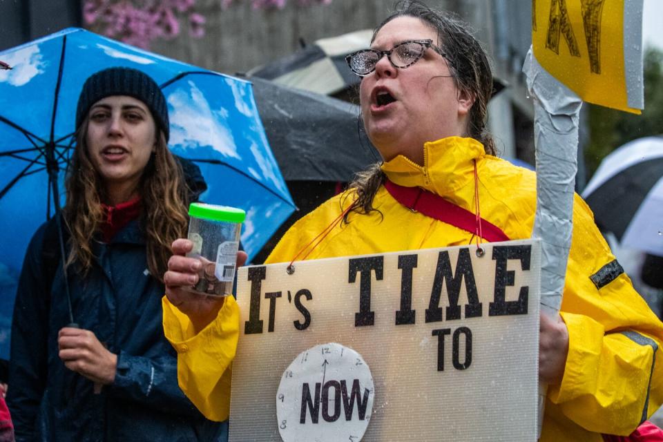 Striking LAUSD workers hold signs and umbrellas