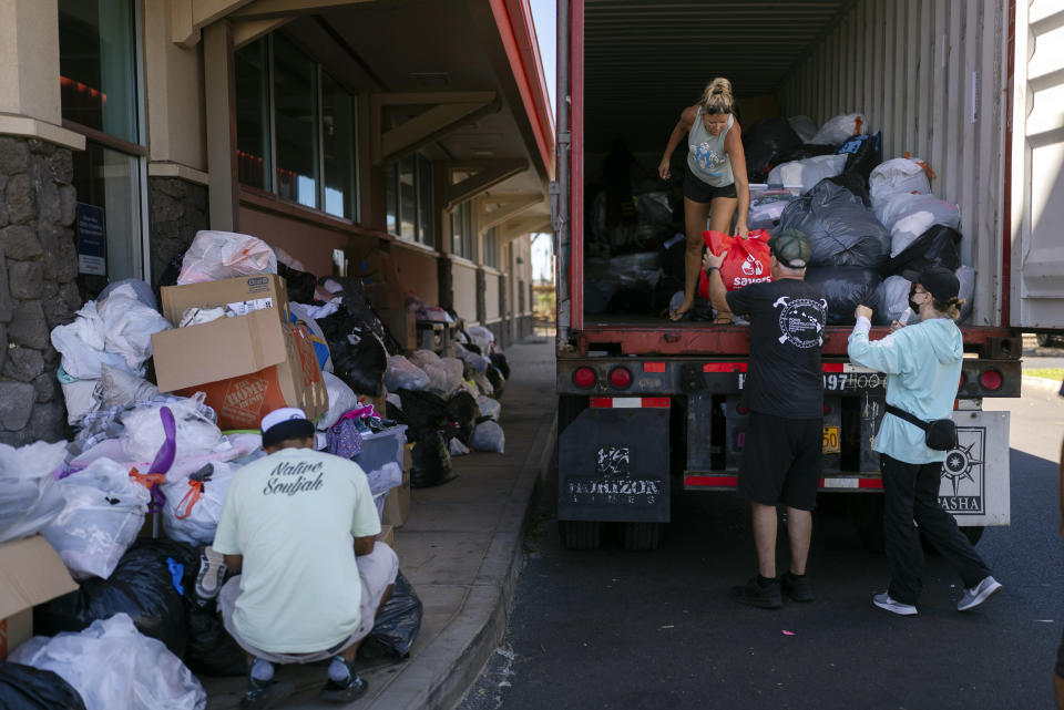 Volunteers unload donated goods at a food and supply distribution center in Lahaina, Hawaii, Thursday, Aug. 17, 2023. The blazes incinerated the historic island community of Lahaina and killed more than 100 people. (AP Photo/Jae C. Hong)