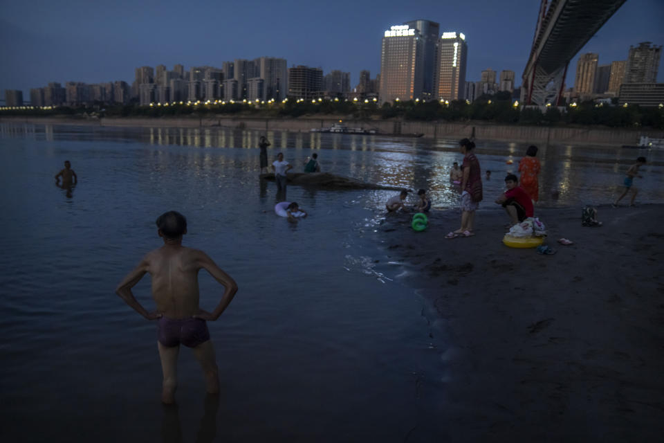 People swim in a shallow portion of the Yangtze River in southwestern China's Chongqing Municipality, Friday, Aug. 19, 2022. The very landscape of Chongqing, a megacity that also takes in surrounding farmland and steep and picturesque mountains, has been transformed by an unusually long and intense heat wave and an accompanying drought. (AP Photo/Mark Schiefelbein)