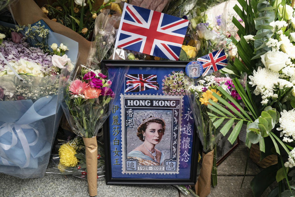 Flowers and a photograph are placed for Queen Elizabeth II outside the British Consulate in Hong Kong, Friday, Sept. 16, 2022. In Britain, Thousands of mourners waited for hours Thursday in a line that stretched for almost 5 miles (8 kilometers) across London for the chance to spend a few minutes filing past Queen Elizabeth II's coffin while she lies in state. (AP Photo/Anthony Kwan)