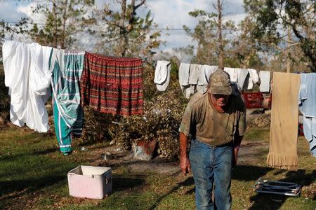 Bernard Sutton, 64, ducks underneath clothes he and his wife hung up to dry after Hurricane Michael destroyed their home in Fountain, Florida, U.S., October 15, 2018. REUTERS/Terray Sylvester