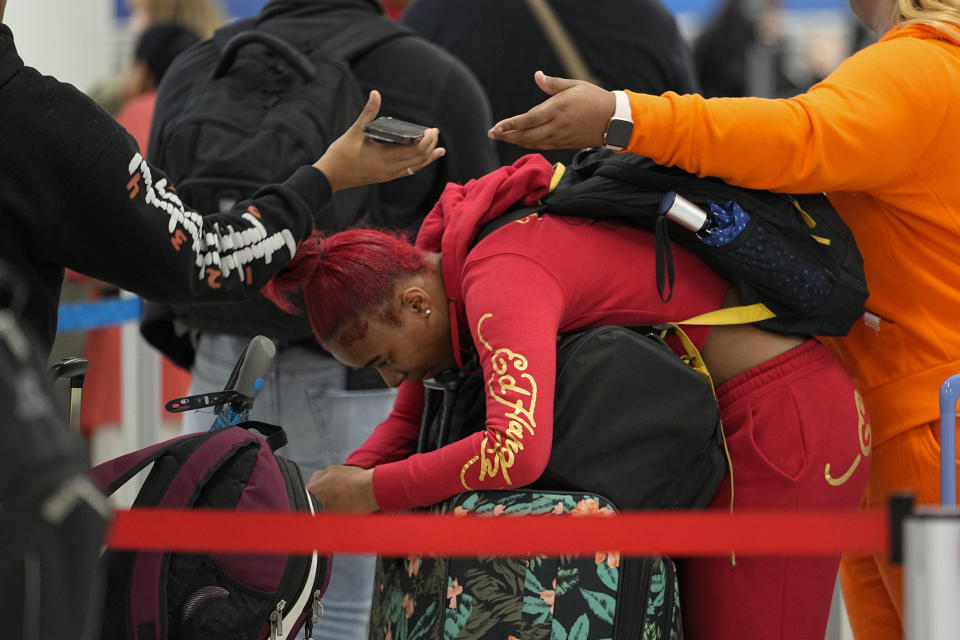 Tamilah Belton rests on her luggage while waiting at the ticket counter before her flight from the Nashville International Airport, Tuesday, Nov. 21, 2023, in Nashville, Tenn. Despite inflation and memories of past holiday travel meltdowns, millions of people are expected to hit airports and highways in record numbers over the Thanksgiving Day break. (AP Photo/George Walker IV)