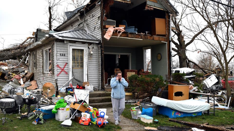 Brittany Oakley checks in with relatives outside of what is left of her home in Lakeview, Ohio, Friday. - Timothy D. Easley/AP