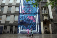 BRISTOL, ENGLAND - AUGUST 17: People walk in front of part of the 'See No Evil' street art project at Nelson Street on August 17, 2012 in Bristol, England. The project, now in its second year, is Europe's biggest street art festival and has attracted top graffiti artists from all over the world. Organizers hope it will continue to be a draw for tourists visiting Bristol, often seen the spiritual home of underground artist Banksy. (Photo by Matt Cardy/Getty Images)