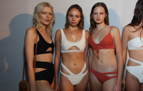 Three models show off their cut-out bikini looks backstage.