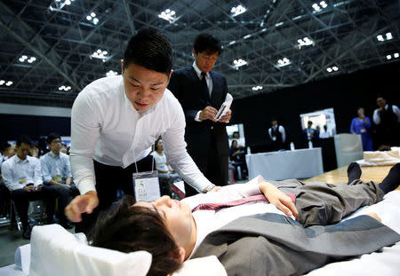 Judges check a model after a funeral undertaker dressed the model, during an encoffinment competition at Life Ending Industry EXPO 2017 in Tokyo, Japan August 24, 2017. REUTERS/Kim Kyung-Hoon