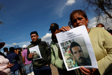 Residents hold pictures of their missing relative at the site where a fuel pipeline ruptured by suspected oil thieves exploded, in the municipality of Tlahuelilpan, state of Hidalgo, Mexico January 19, 2019. REUTERS/Henry Romero