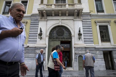 People walk in front the National Bank headquarters in Athens, Greece, June 22, 2015. REUTERS/Marko Djurica