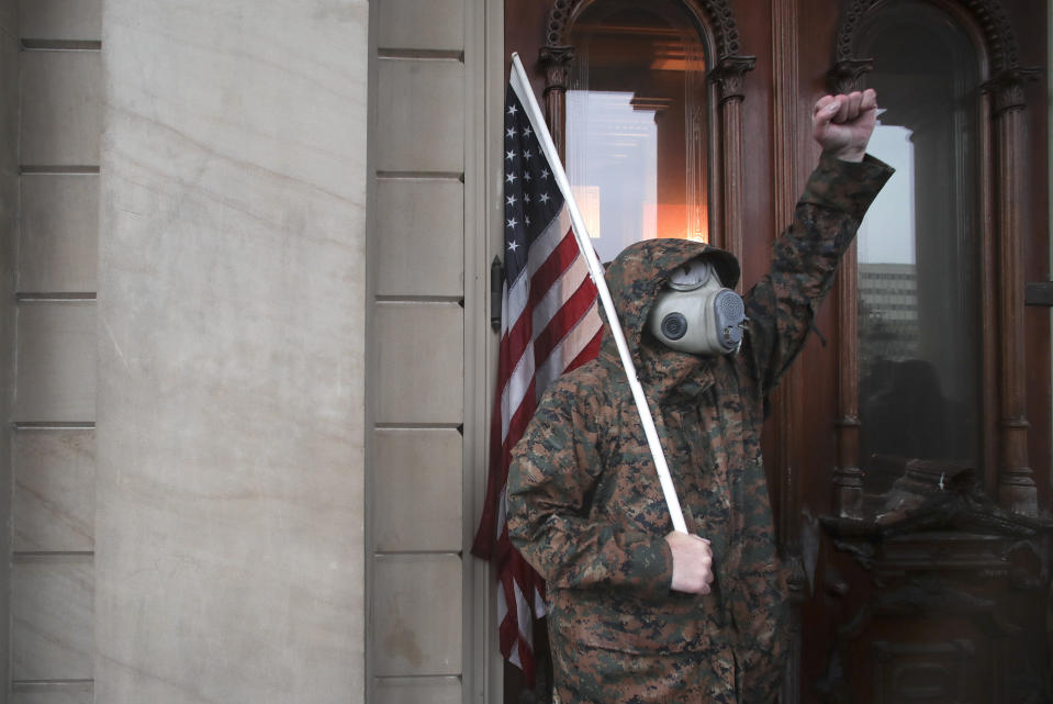 A protester raises his fist at the doors of the State Capitol during a rally against Michigan’s coronavirus stay-at-home order in Lansing, Mich., Thursday, May 14, 2020. (AP Photo/Paul Sancya)