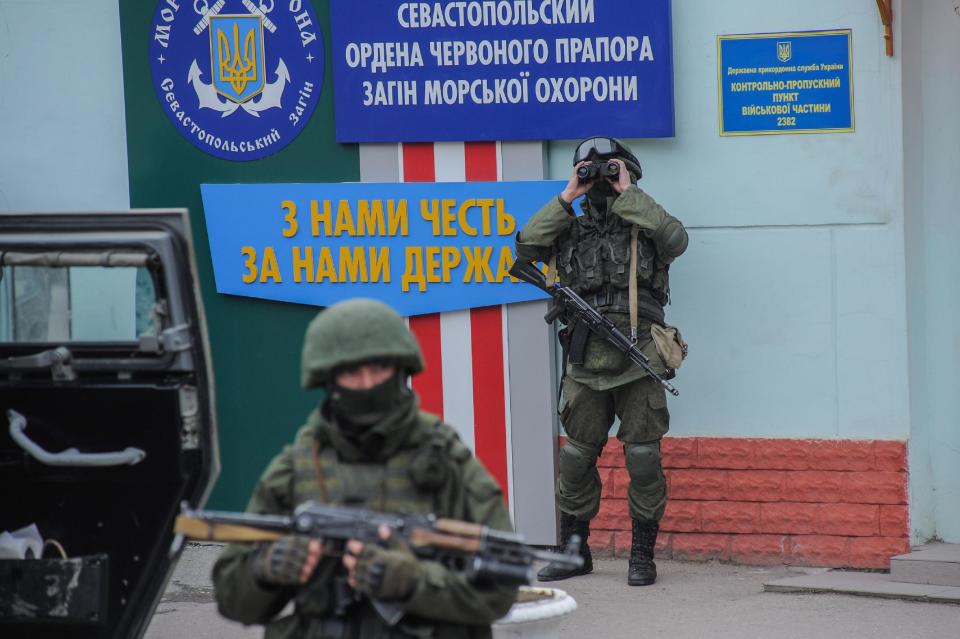 Troops in unmarked uniforms stand guard as they taking control the the Caost Guard offices in Balaklava on the outskirts of Sevastopol, Ukraine, Saturday, March 1, 2014. An emblem on one of the vehicles and their number plates identify them as belonging to the Russian military. Ukrainian officials have accused Russia of sending new troops into Crimea, a strategic Russia-speaking region that hosts a major Russian navy base. The Kremlin hasn't responded to the accusations, but Russian lawmakers urged Putin to act to protect Russians in Crimea. (AP Photo/Andrew Lubimov)