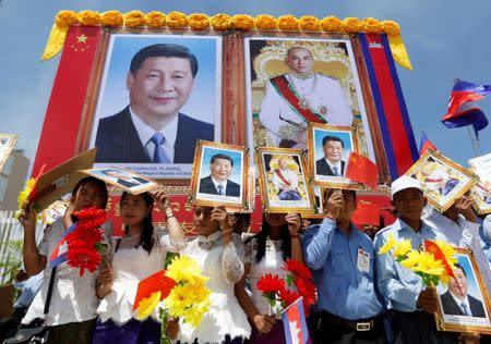 People stand next to portraits of Chinese President Xi Jinping (L) and Cambodian King Norodom Sihamoni during Xi Jinping's welcoming ceremony at Phnom Penh, Cambodia October 13, 2016. REUTERS/Samrang Pring