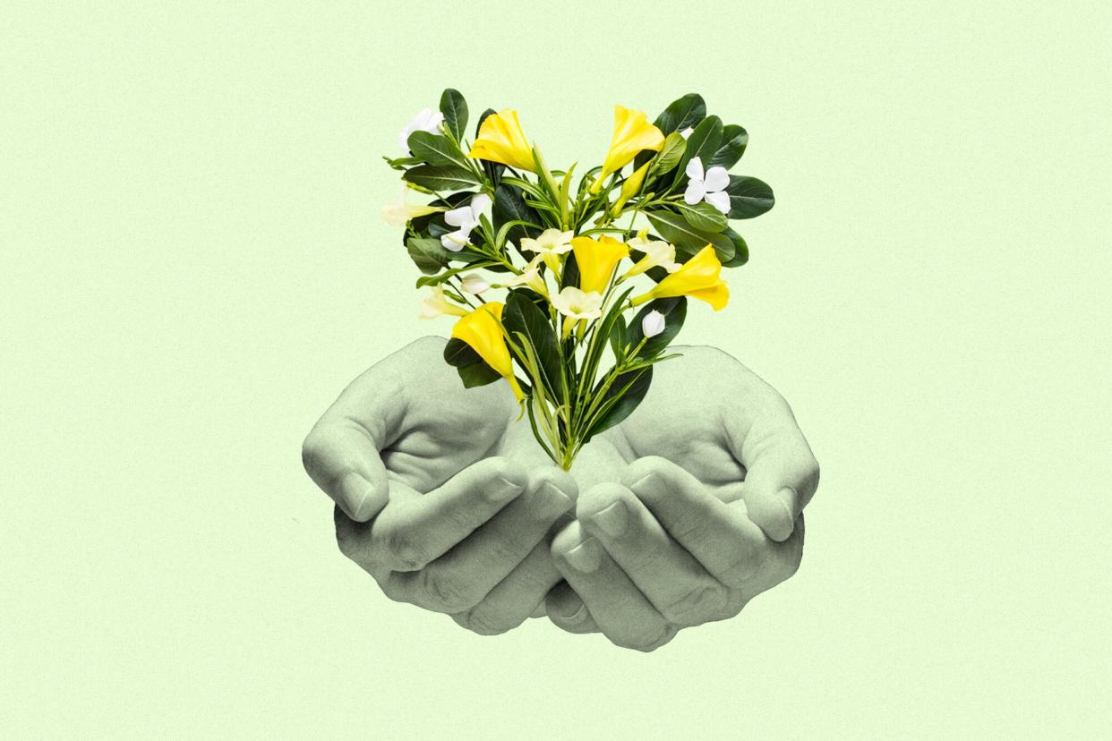 two cupped hands under a heart made of flowers on a green background