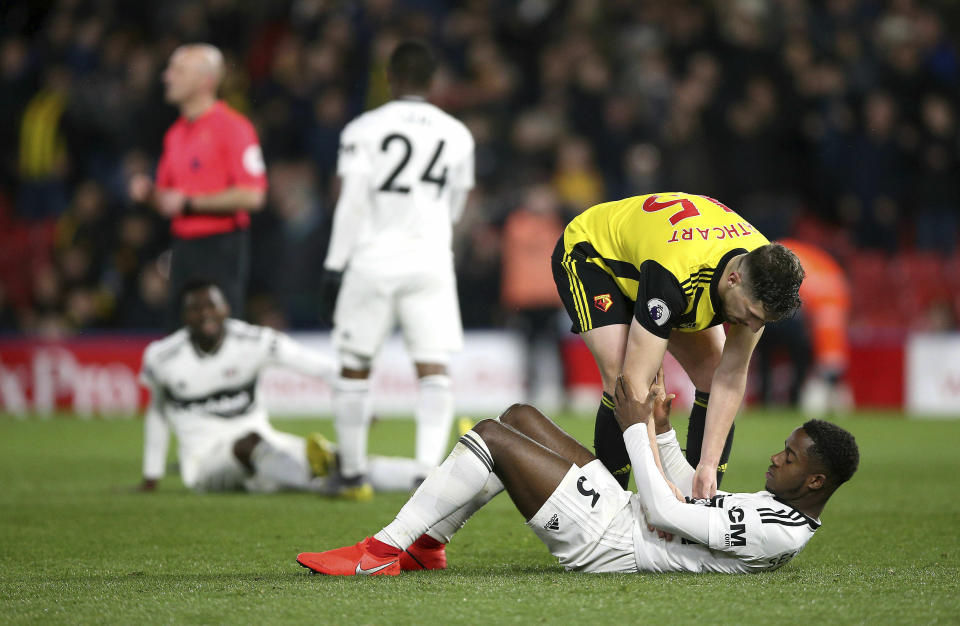 Fulham's Ryan Sessegnon is consoled by Watford's Craig Cathcart after the final whistle of the  English Premier League soccer match against Watford at Vicarage Road, Watford, England, Tuesday, April 2, 2019. Three managers, 24 losses and around $130 million later, Fulham has been relegated from the Premier League. The London club's return to the English top flight will last just one season after its demotion was confirmed with a 4-1 loss at Watford on Tuesday. (Nigel French/PA via AP)