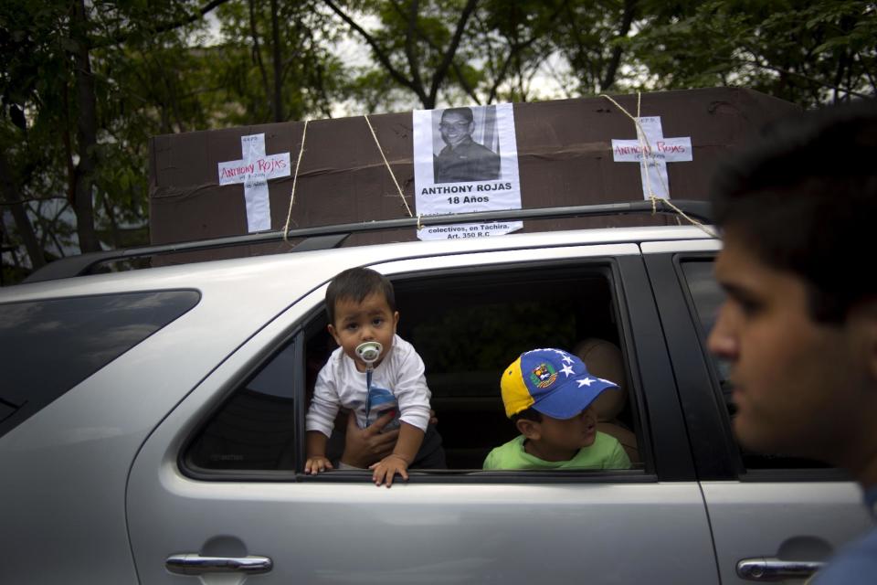 A car with a mock coffin and the name of a dead protester pasted on it, drives through the streets of Caracas during a march of remembrance for those fallen during the protests in Venezuela, Tuesday, April. 15, 2014. As Venezuela’s opposition is resuming negotiations with the government doubts are arising that the talks will produce a breakthrough. (AP Photo/Ramon Espinosa)