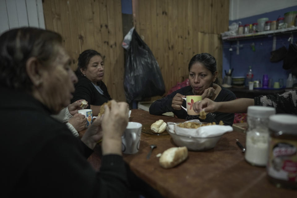 Volunteers eat before distributing food and serving hot meals at a soup kitchen in Buenos Aires, Wednesday, May 10, 2023. Many people rely on daily food handouts amid galloping inflation. (AP Photo/Victor R. Caivano)