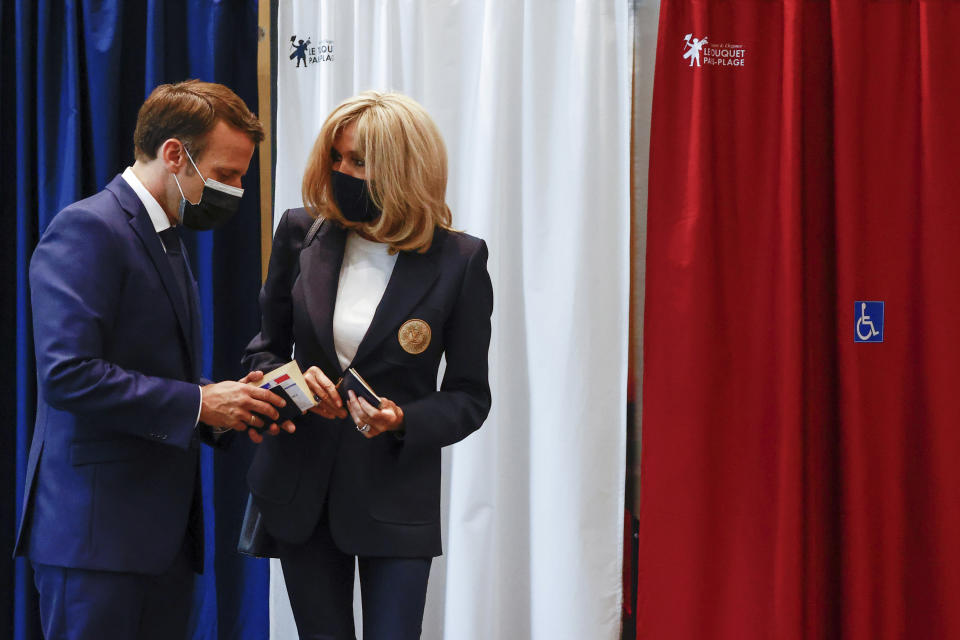 French President Emmanuel Macron chats with his wife Brigitte during the first round of French regional and departmental elections, in Le Touquet-Paris-Plage, northern France, Sunday, June 20, 2021. The elections for leadership councils of France's 13 regions, from Brittany to Burgundy to the French Riviera, are primarily about local issues like transportation, schools and infrastructure. But leading politicians are using them as a platform to test ideas and win followers ahead of the April presidential election. (Christian Hartmann/Pool via AP)